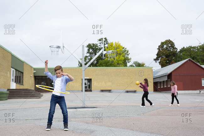 Boy spinning plastic hoop on school yard