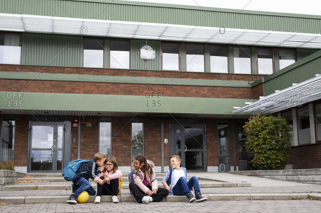 Children sitting in front of school building