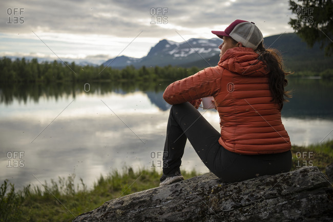 Woman sitting at lake and looking at view