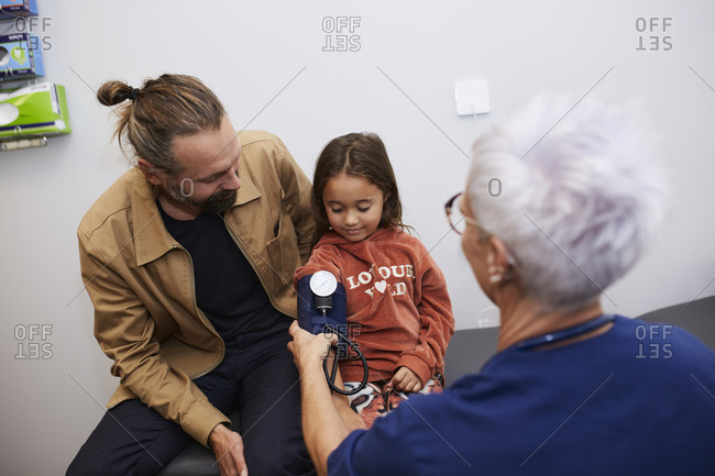 Doctor examining father and daughter in health center