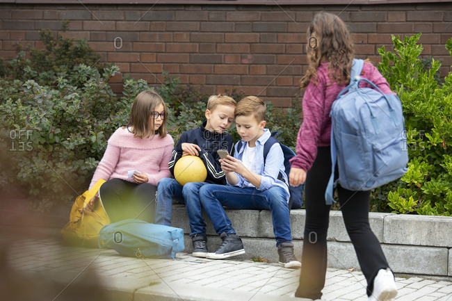 Children looking at cell phone in front of school building