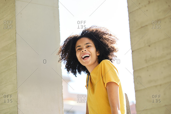 Curly hair student laughing while standing at university