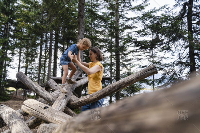 Mother assisting little daughter walking on top of wooden logs