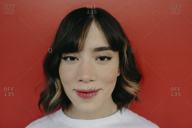 Young woman with short highlighted hair against red background