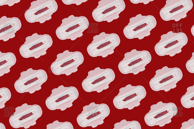 Pattern of bloodstained sanitary pads against red background