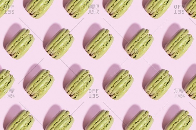 Pattern of green macaroon cookies against pink background
