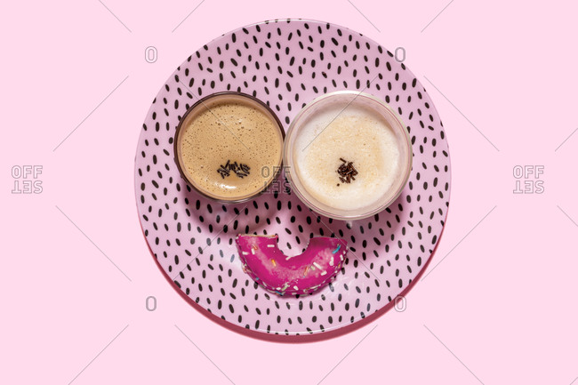 Anthropomorphic face made of plate- halved doughnut and two glasses of coffee