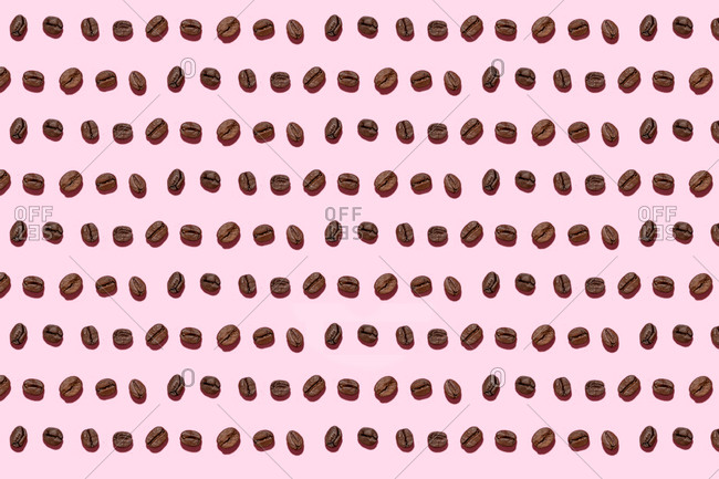 Pattern of roasted coffee beans against pink background