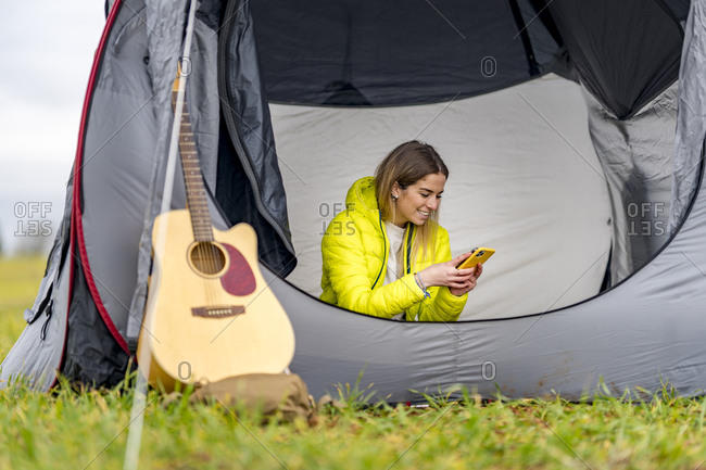 Young woman using smart phone inside tent