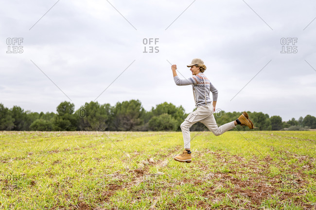 Young man jumping and posing mid-air in grassy field