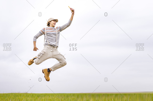 Young man taking selfie mid-jump