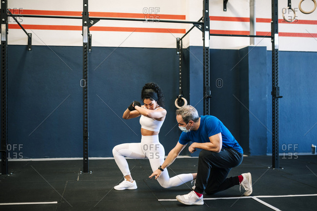 Male instructor training female athlete in gym during COVID-19
