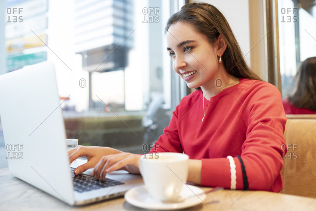 Smiling woman using laptop while sitting in cafe