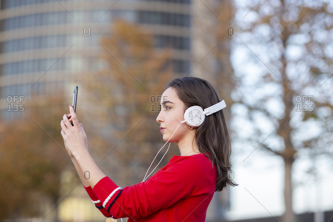 Woman with headphones taking selfie on mobile phone