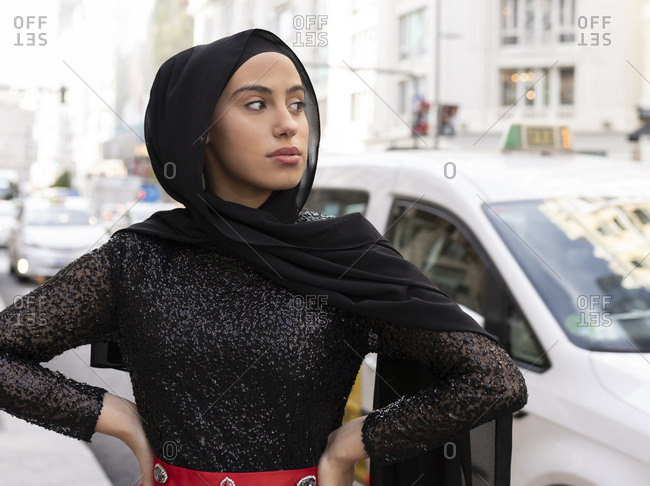 Portrait of young beautiful woman wearing black hijab posing on city street