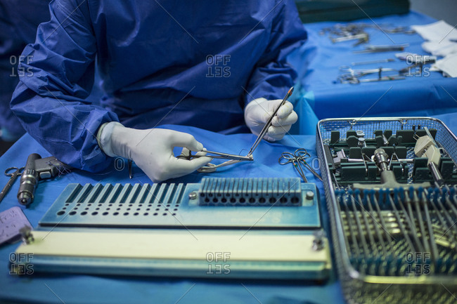 Male orthopedic surgeon preparing tweezers for operation in ICU