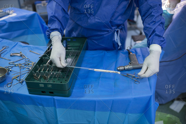 Male orthopedic surgeon preparing knee tendon in operating room