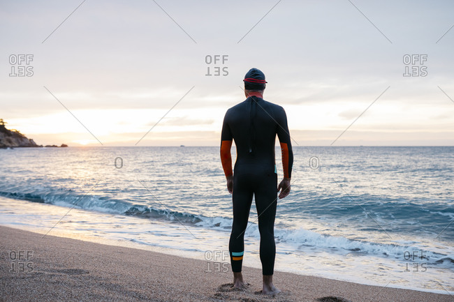 Male swimmer admiring sea at sunset