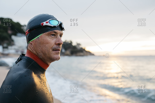 Portrait of male swimmer admiring sea at sunset
