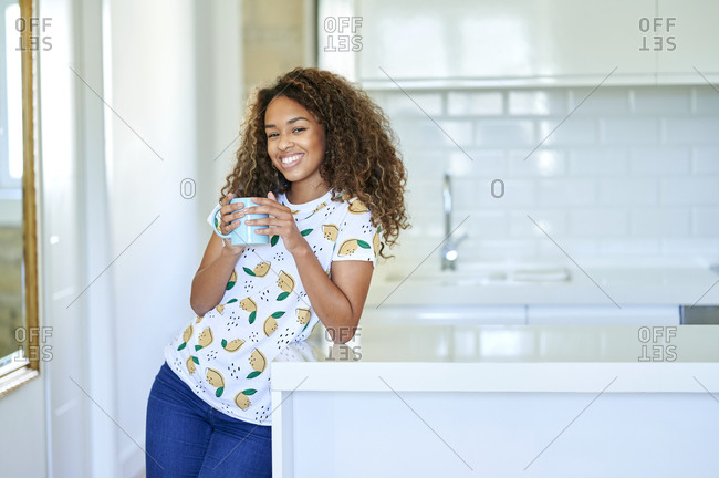 Smiling young holding coffee cup in kitchen at home