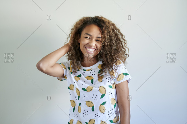 Afro young woman with hand in hand in hair against white wall