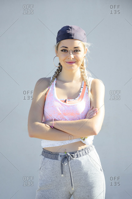 Confident athlete wearing cap standing with arms crossed against wall