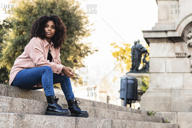 Fashionable young woman with cool attitude sitting on staircase in city