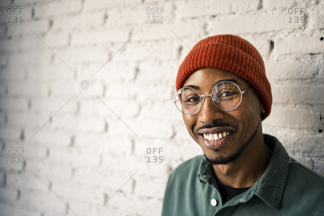 Smiling man wearing eyeglasses against white brick wall