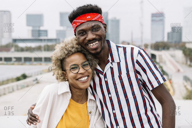Smiling man standing with arm around friend in city