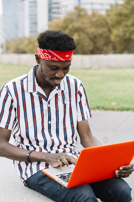 Smiling man using laptop while sitting on bench