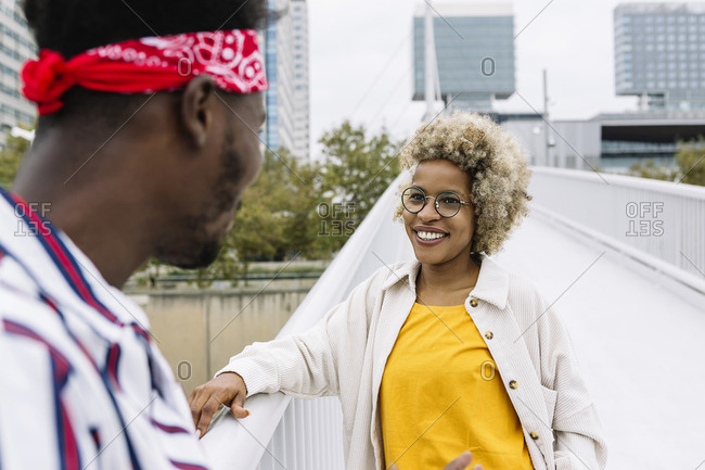 Smiling woman standing with male friend on bridge in city