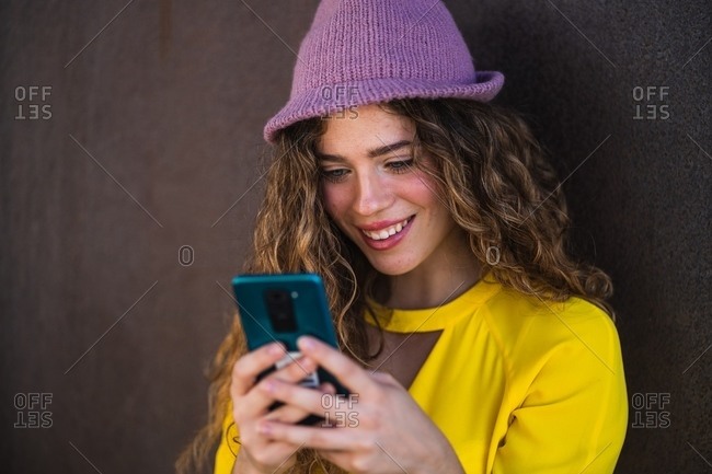 Cheerful young woman using smartphone on street