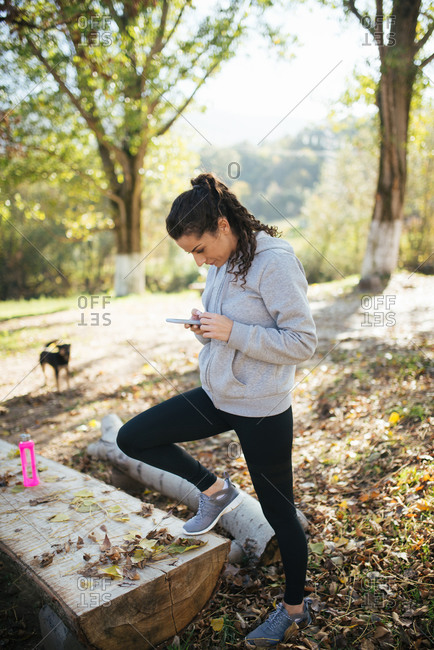 Young sportswoman using smartphone in the park
