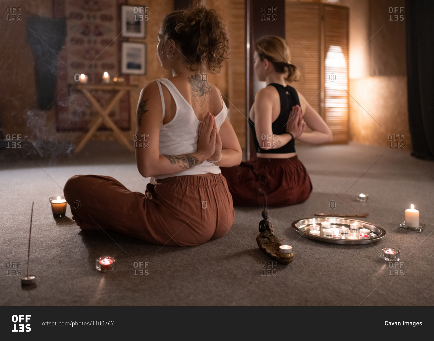 Unrecognizable women meditating with hands behind backs together