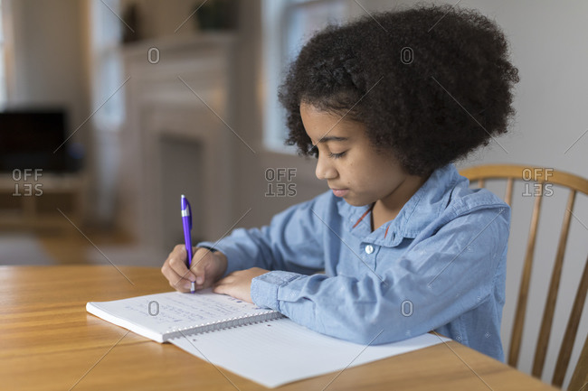 Ten year-old bi-racial girl doing homework at table