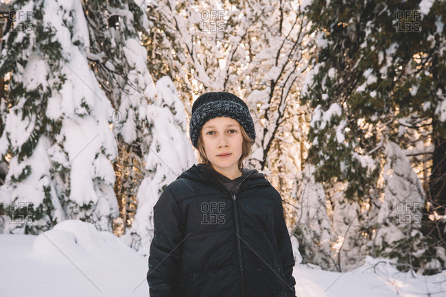 Young Boy in Beanie Stands in a Snowy Scene.