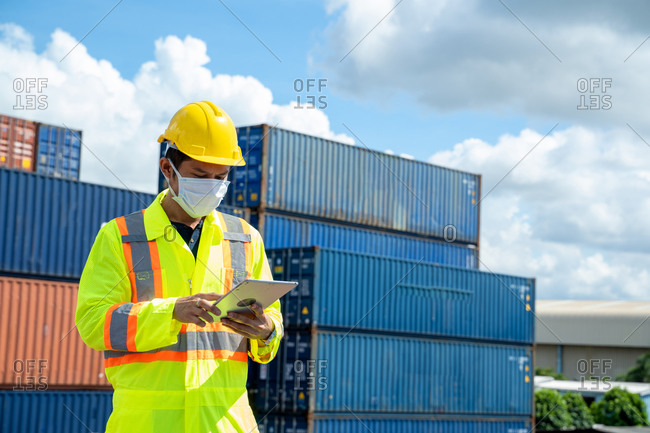 Young worker man with digital tablet at container terminal port,