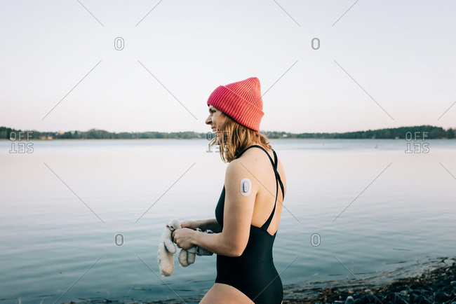 Woman entering the calm water ready for cold water swimming in Sweden