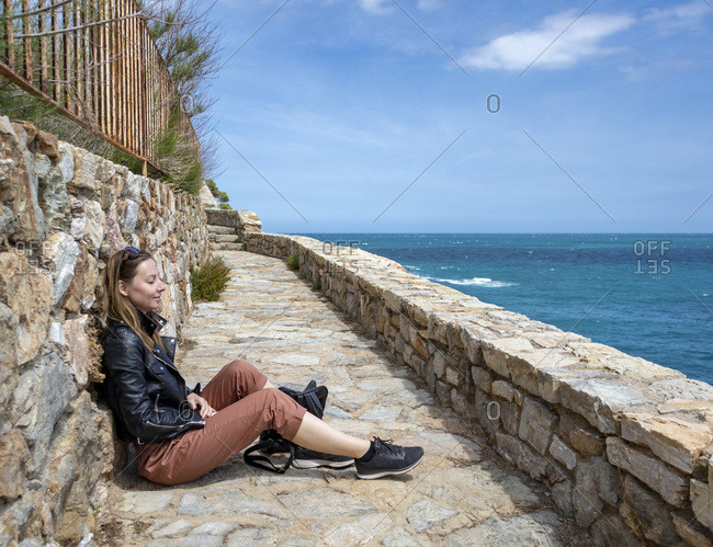 Cheerful girl dressed in red enjoying the coast and looking at the sea