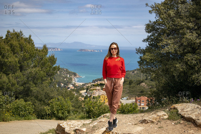 Cheerful girl dressed in red enjoying the coast and looking at the sea