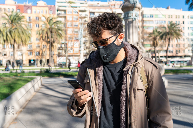 man with face mask and sunglasses calling on the phone on the street