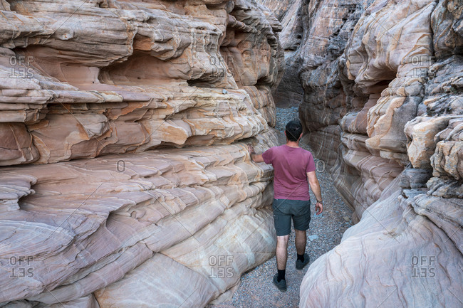 Young man walking through White Domes Slot Canyon (MR), Valley of Fire State Park, Nevada, USA