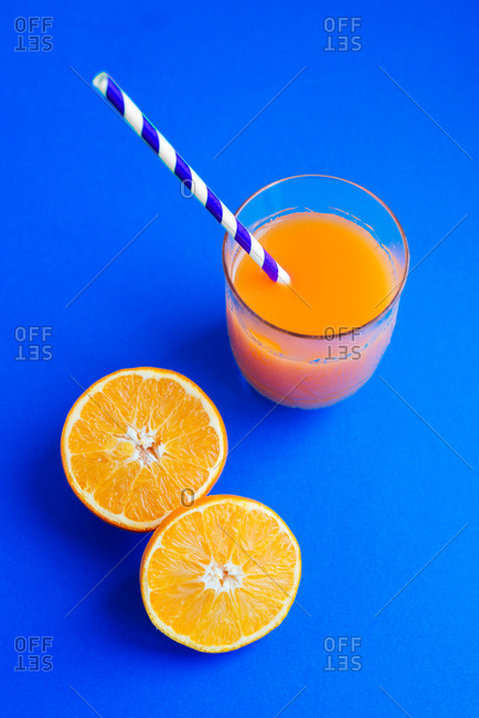 A glass of orange juice on a table in a blue interior. Stock Photo by  puhimec