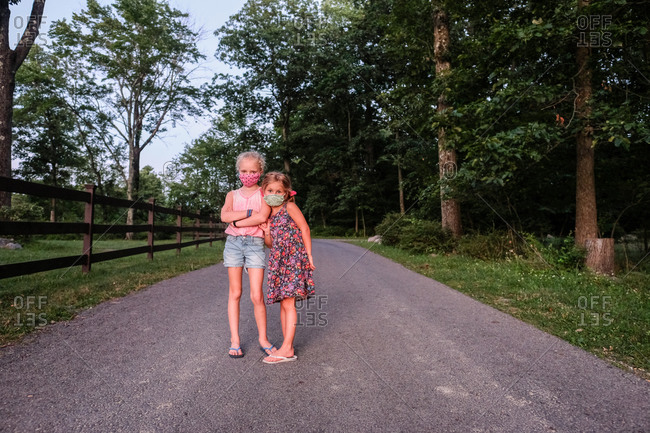 portrait of two girls wearing masks on road in the woods in summer