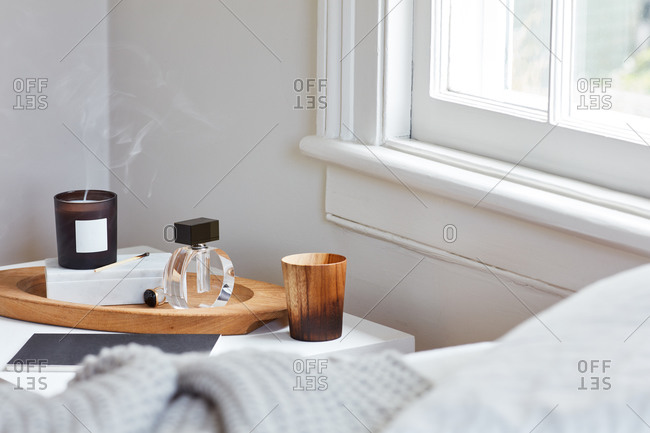 Scented candle at bedside table with perfume