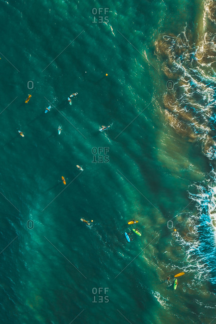Aerial view of people surfing the waves in the ocean near Sakoneta beach in Gipuzkoa, Euskadi, Spain.