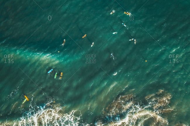 Aerial view of people surfing the waves in the ocean near Sakoneta beach in Gipuzkoa, Euskadi, Spain.