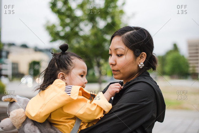 Close up of a Native American woman hugging and carrying her daughter in her arms