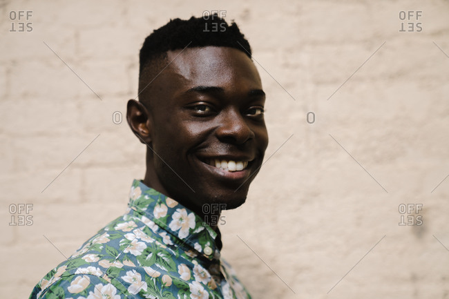 Horizontal profile shot of a model grinning in front a wall