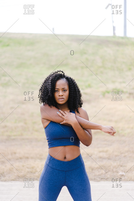 Close up portrait of a strong focused woman stretching outdoors